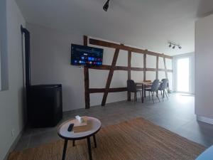 ein Wohnzimmer mit einem Tisch und einem Fernseher an der Wand in der Unterkunft Au ptit Hottonruy in Stavelot