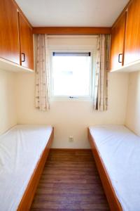 two beds in a room with a window at Chalet nabij water in Langweer in Langweer