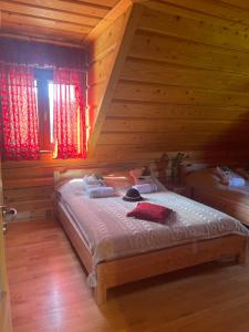 Łóżko w pokoju z drewnianymi ścianami i oknami w obiekcie Góralska Chata & Spa w Muszynie