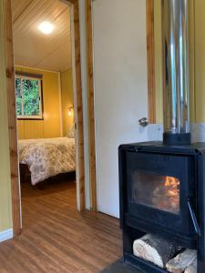 a room with a fireplace and a bedroom with a bed at CABAÑAS RÜPÜ PUYUHUAPI in Puerto Puyuhuapi