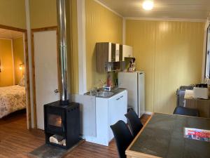 a kitchen with a stove and a kitchen with a table at CABAÑAS RÜPÜ PUYUHUAPI in Puerto Puyuhuapi +8 photos