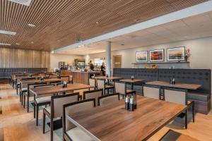 una sala da pranzo con tavoli e sedie in legno di Home Hotel Helma a Mo i Rana