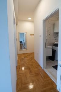 een hal die leidt naar een badkamer met een houten vloer bij Apartman 20 in Trebinje +15 foto's