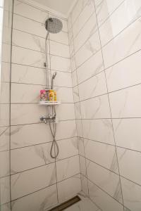 een douche in een badkamer met witte tegels bij Apartman 20 in Trebinje