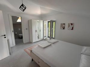 Un dormitorio blanco con una cama y un baño. en Quince Luxury Apartment, en Ðenovići