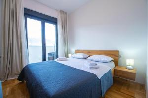 een slaapkamer met een blauw bed en een groot raam bij Apartman 20 in Trebinje