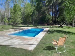 a chair sitting in the grass next to a swimming pool at La Venecia Cabañas in San Rafael