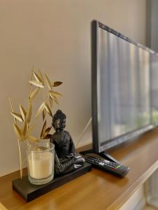 a small buddha statue sitting on a desk next to a television at Casinha dos Carris in Valença