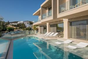 a house with a swimming pool with white chairs at Beachfront Villa Edem Dedicated Beach Space - Heated Pool in Agios Nikolaos