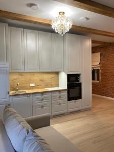 a kitchen with white cabinets and a chandelier at Apartamentai Domus Antiqua in Zarasai