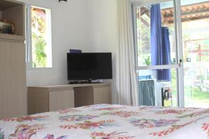 1 dormitorio con 1 cama, TV y ventana en Pipa Hawaii Suites, en Pipa