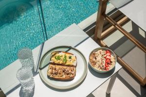 a table with a plate of food next to a pool at Edem Boutique Hotel in Agios Nikolaos