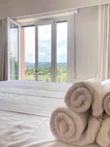 a pile of towels on a bed in a room with windows at Home & B in Arezzo