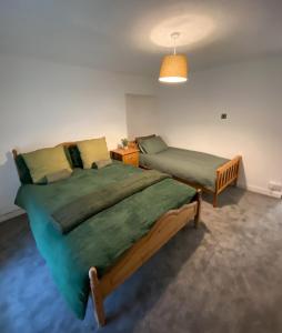 a bedroom with two beds and a night stand at Lime Cottage in Mountain Ash