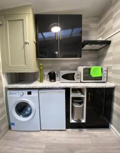 a kitchen with a washing machine and a microwave at Lime Cottage in Mountain Ash