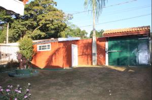 Un edificio naranja con una puerta verde en un patio. en Recanto Boa Ideia, en Campo Alegre