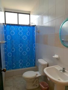a bathroom with a toilet and a blue shower curtain at Hotel Belamar in La Libertad +39 photos