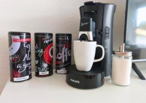a row of coffee cups and a coffee maker on a shelf at Rooftop Apartments - Modernes Studioapartment für 3 Personen in Langenau +3 photos