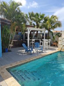 a swimming pool with two blue chairs and a table and a pool at Sandcastle Beach Apartments in Palm-Eagle Beach