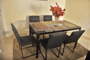 a dining room table with chairs and a vase of flowers at Location Villa à Agoè lome in Atchavé