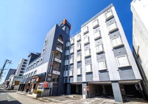 a tall white building on a city street at APA Hotel Miyazaki Nobeoka Ekimae in Nobeoka
