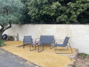 three chairs and a table next to a wall at La cigale des cantarelles in Mornas +2 photos