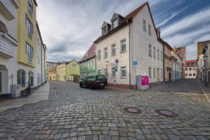 eine Straße mit einem Auto auf einer Kopfsteinpflasterstraße in der Unterkunft Des Türmers Tochter Apartment in Delitzsch