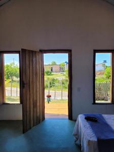 a room with a bed and two windows and a door at Chalés Costa Amar in Porto Seguro +6 photos