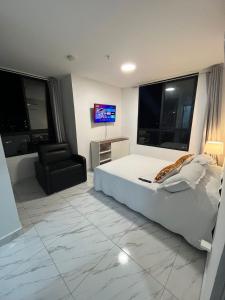 a bedroom with a bed and a chair and a television at Espectacular aparta estudio in Panama City