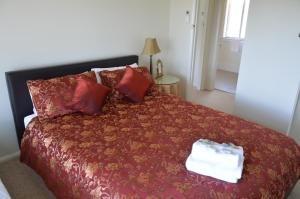 巴瑟斯特BATHURST GOLDFIELDS RESIDENCE on MOUNT PANORAMA的一间卧室配有一张带红色毯子和枕头的床。