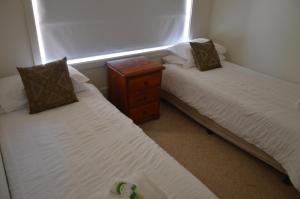 two twin beds in a room with a window at BATHURST GOLDFIELDS RESIDENCE on MOUNT PANORAMA in Bathurst