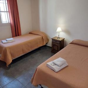 a room with two beds and a table with a lamp at Casa bosque de Sol in Malargüe