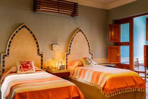 a bedroom with two beds with orange and white sheets at Hotel Boutique Casa San Angel in Mérida