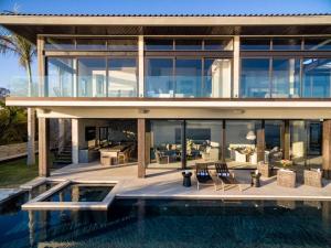 a large glass house with a pool in front of it at Beachfront house in Kupuri Punta Mita in Puerto Vallarta