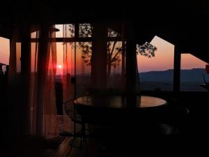 a room with a table and a window with a sunset at Na'raucária in Cambará