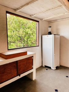a small kitchen with a refrigerator and a window at Casa da Mata Corumbau in Corumbau