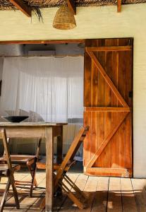 a wooden barn door with a table and chairs at Casa da Mata Corumbau in Corumbau