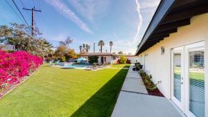 a house with a lawn and a yard with pink flowers at Mini Resort is Yours fun in the sun with Massive Back Yard A please surprise upon arrival at your mini resort in Palm Desert