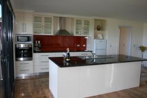 a kitchen with white cabinets and a black counter top at Black Rock Retreat in Howth