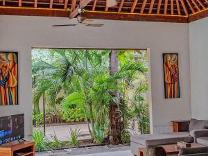 a living room with a large window with a palm tree outside at Senang Private Villa in Gili Trawangan