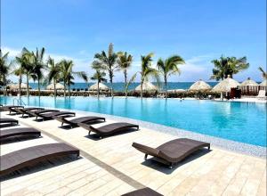 Una piscina con tumbonas y el océano. en 403 - Samaria Club de Playa, en Gaira