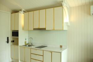 a kitchen with yellow cabinets and a sink at Grand Florida芭提雅带免费游泳池温泉桑拿浴和健身房瑜伽室私家海滩公寓E206 in Na Jomtien