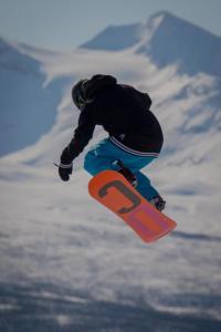 a person doing a trick on a snowboard in the air at Målselv Fjellandsby - Cabins in Bardufoss