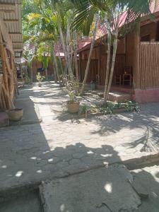 a courtyard with palm trees and a building at Sasak Lombok Bungalow in Kuta Lombok