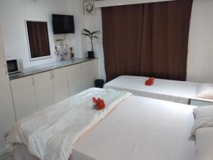 two beds in a hotel room with red flowers on them at Nadi Airport Transit Hotel in Nadi