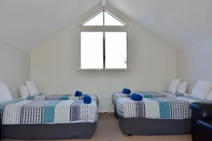 two beds in a room with a window at Ocean View Beach House, Margaret River in Gnarabup