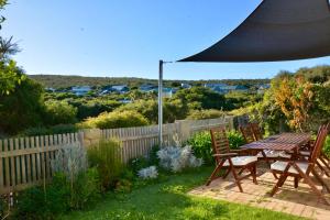 a patio with a table and chairs in a garden at Ocean View Beach House, Margaret River in Gnarabup