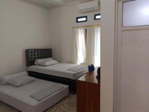two beds in a small room with a window at Sibento Komodo Homestay in Labuan Bajo