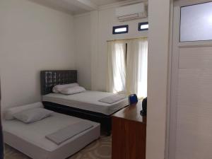 two beds in a small room with a window at Sibento Komodo Homestay in Labuan Bajo