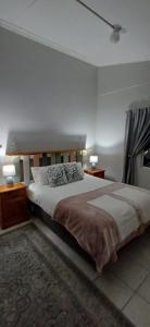 a bedroom with a large bed with two lamps and a rug at Winemaker's Rest in Oudtshoorn